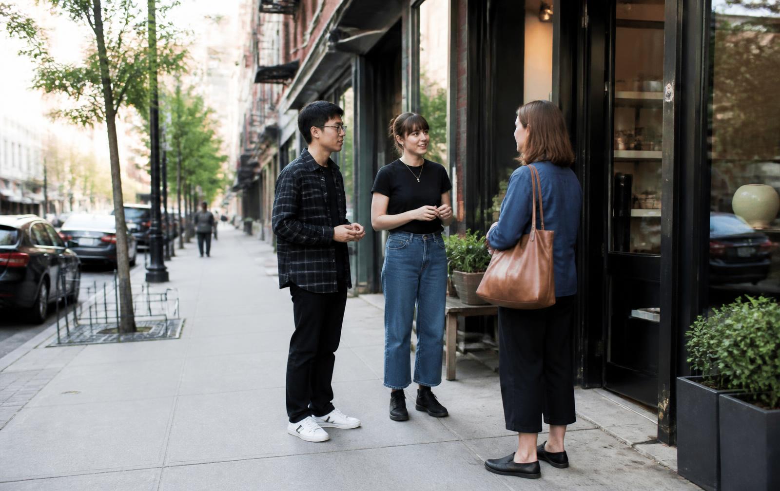Two brand representatives having a face-to-face conversation with a passerby outside a city storefront